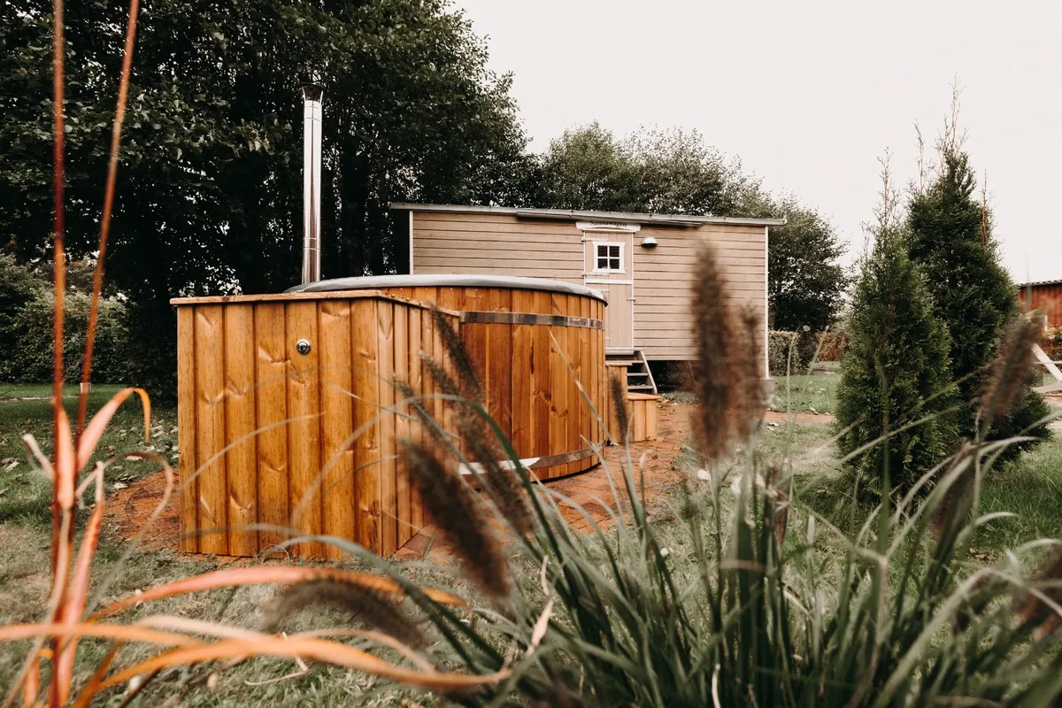 Hölzerner Hot Tub im Garten des Okelmann's neben einem Saunawagen